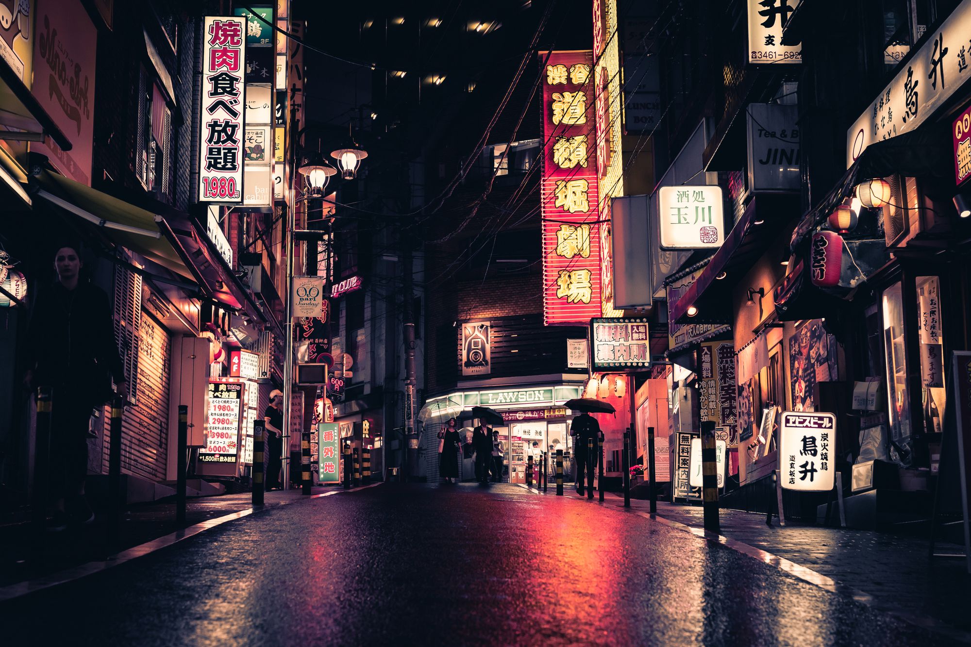 A narrow street at night lit by red and white neon signs