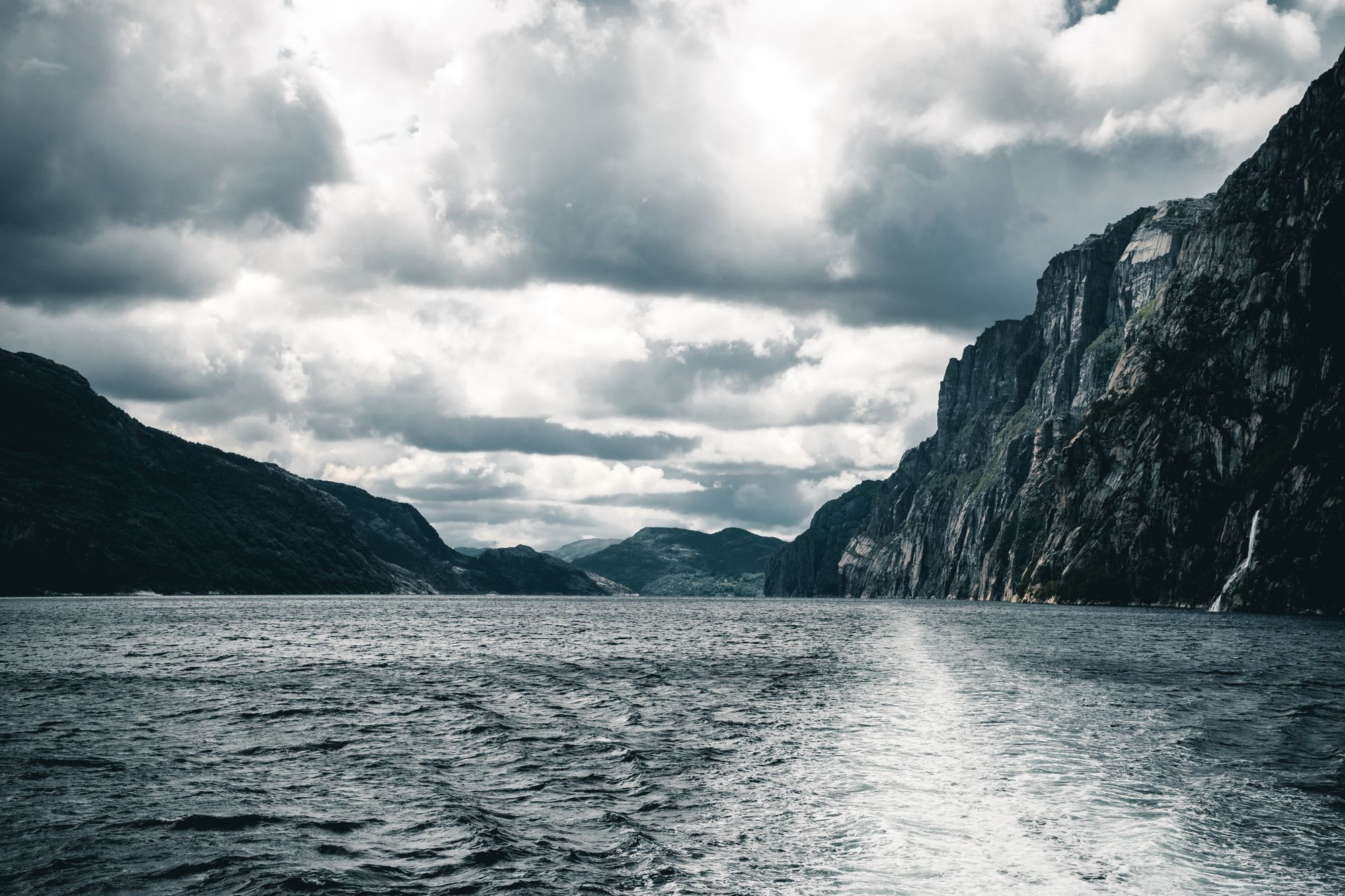 A fjord between tall cliffs under heavy clouds
