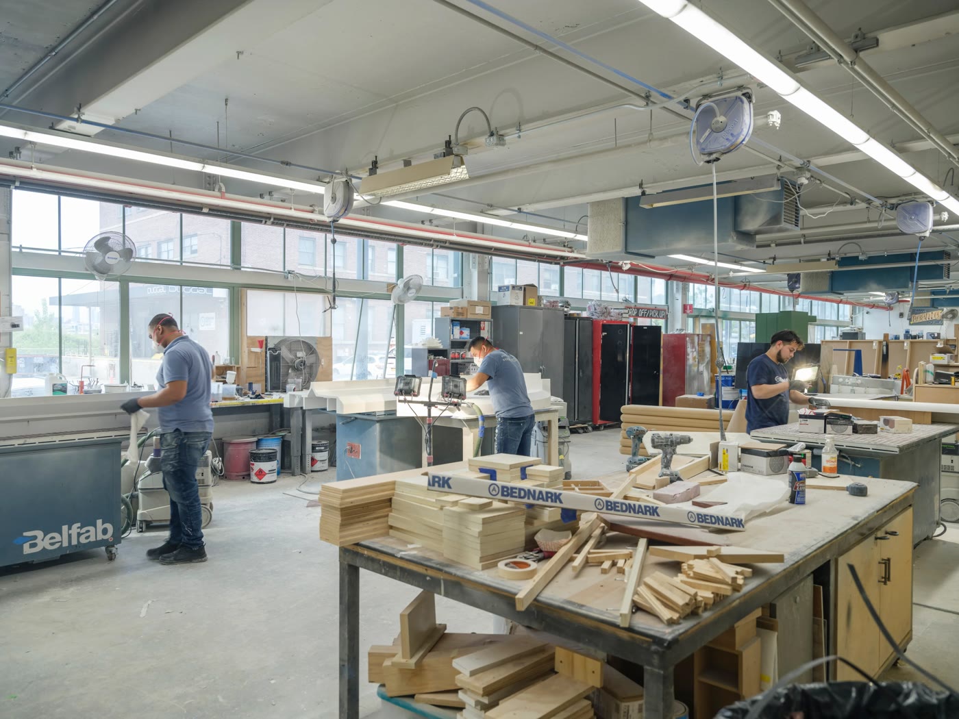 Three Bednark fabricators working at benches among cut plywood and stencilled parts
